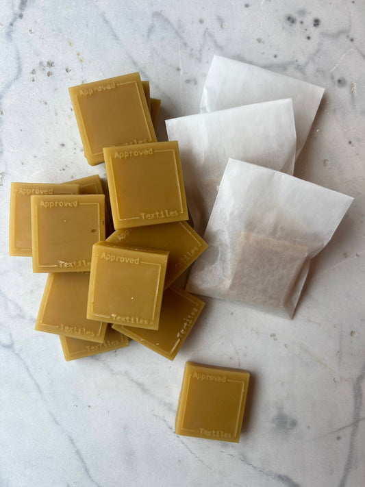 25g block of hand-poured beeswax stamped with the Approved Textiles mark, sourced from Huff's Honey Farm in Trout Run, Pennsylvania.