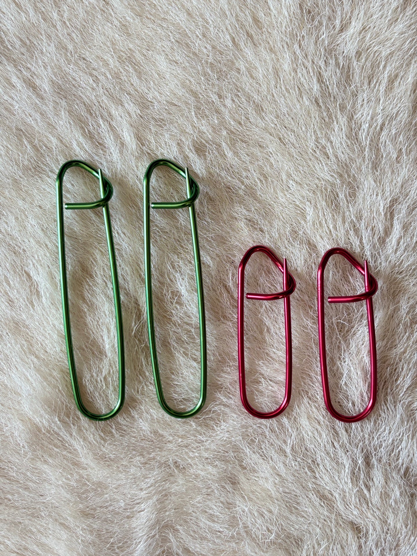Four metal knitting stitch holders in two different sizes