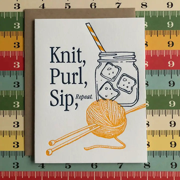 A white greeting card with a kraft envelope, featuring the text 'Knit, Purl, Sip, Repeat.' and illustrations of a mason jar with a striped straw, ice cubes, and orange yarn with knitting needles.