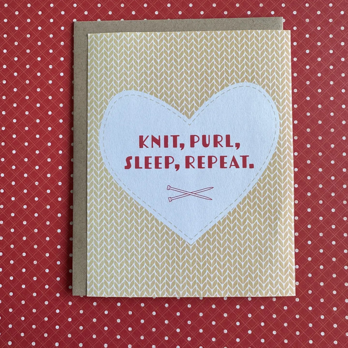 A square greeting card with a kraft envelope, featuring a cream and beige knit pattern background, a central white heart shape, and the text 'KNIT, PURL, SLEEP, REPEAT.' in red